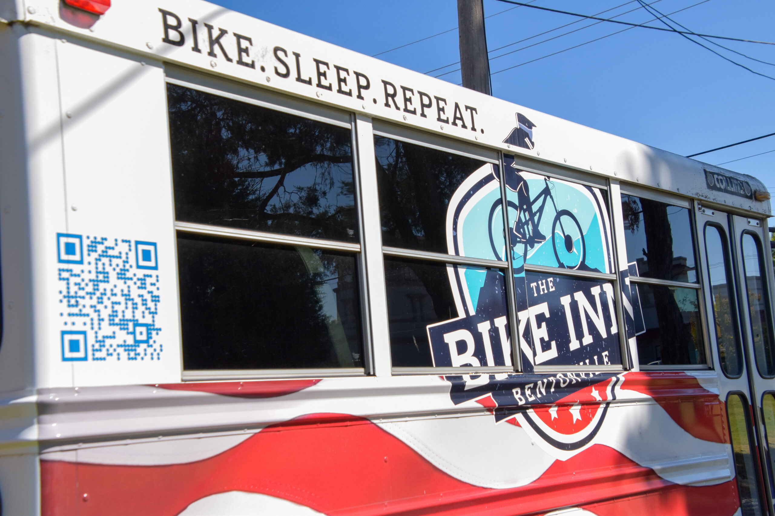 The Bike Inn Freedom Shuttle bus with the Bike. Sleep. Repeat. logo, used for group trips around Bentonville